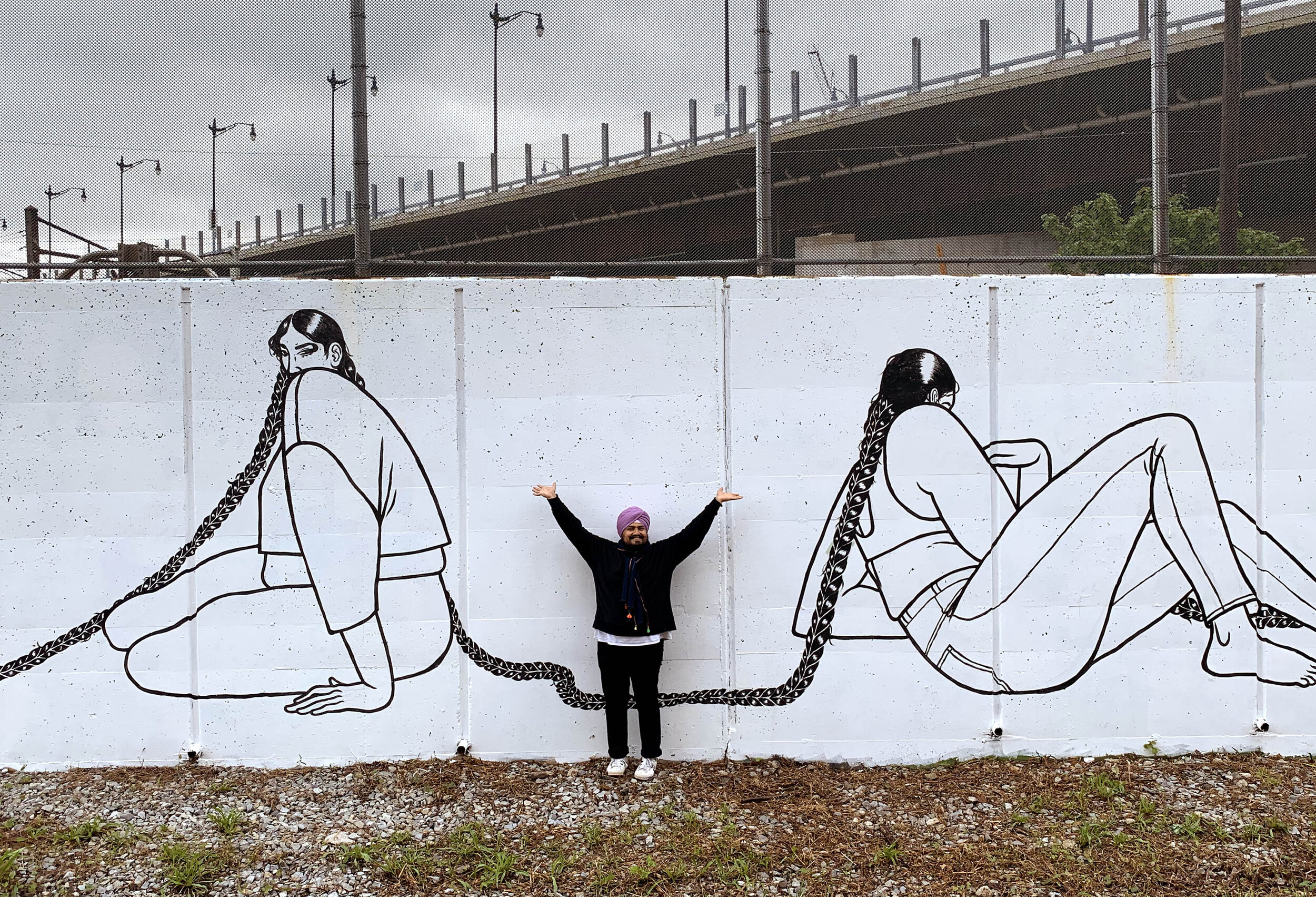 Immagine del murale DC, Connect, di Jasjyot Singh Hans con l'artista davanti.