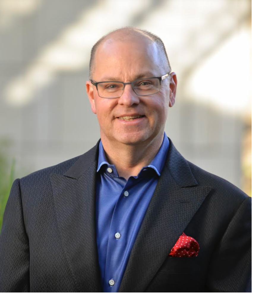 Professor Mark Lemley faces the camera wearing a dark blue suit and bright blue shirt, with a blurred background